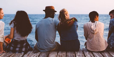 young people sitting on a dock backs to camera