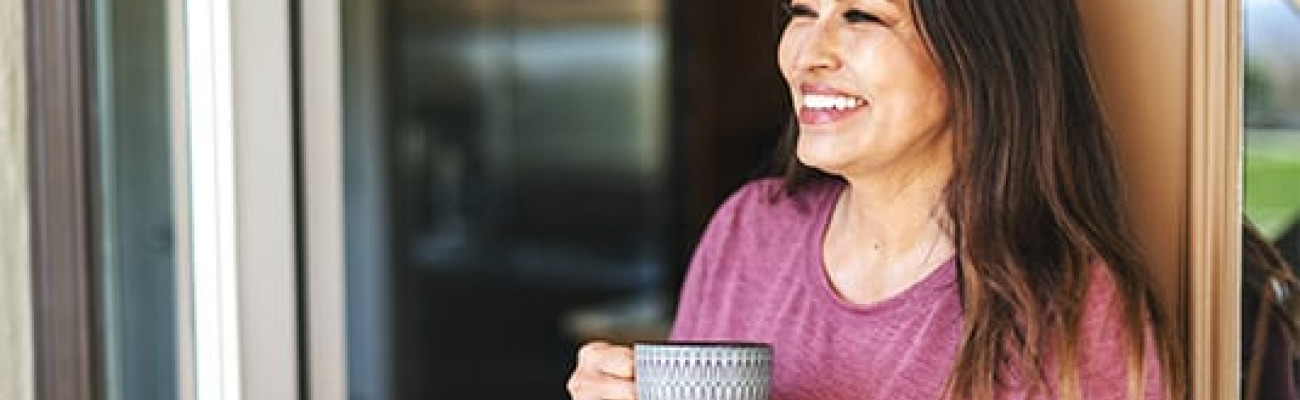 woman in the doorway smiling with coffee