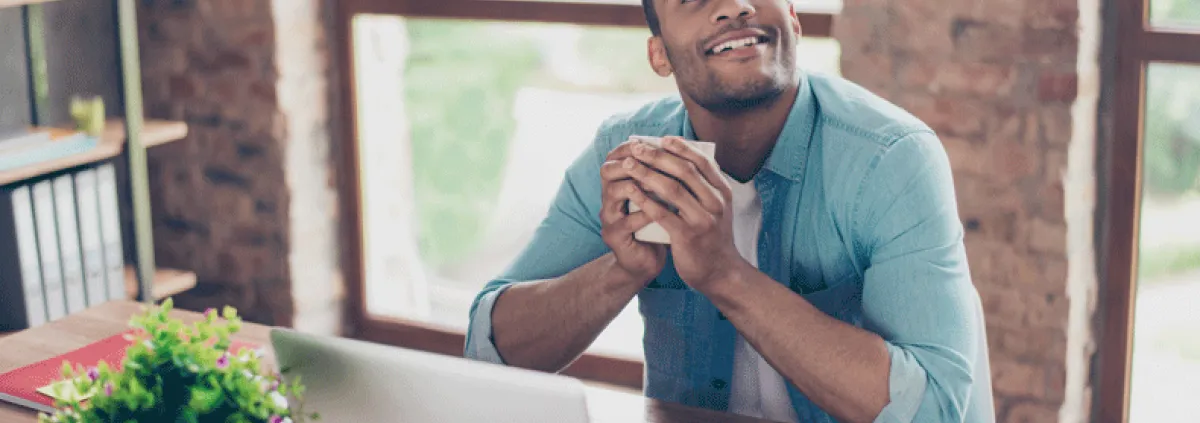 man looking up and smiling while holding coffee