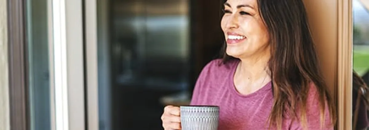 woman in the doorway smiling with coffee
