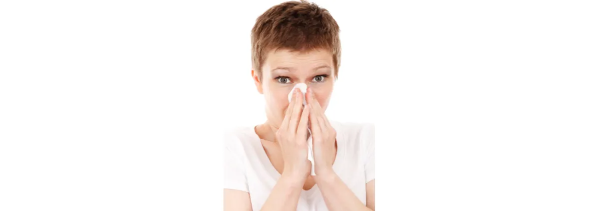 woman sneezing into tissue